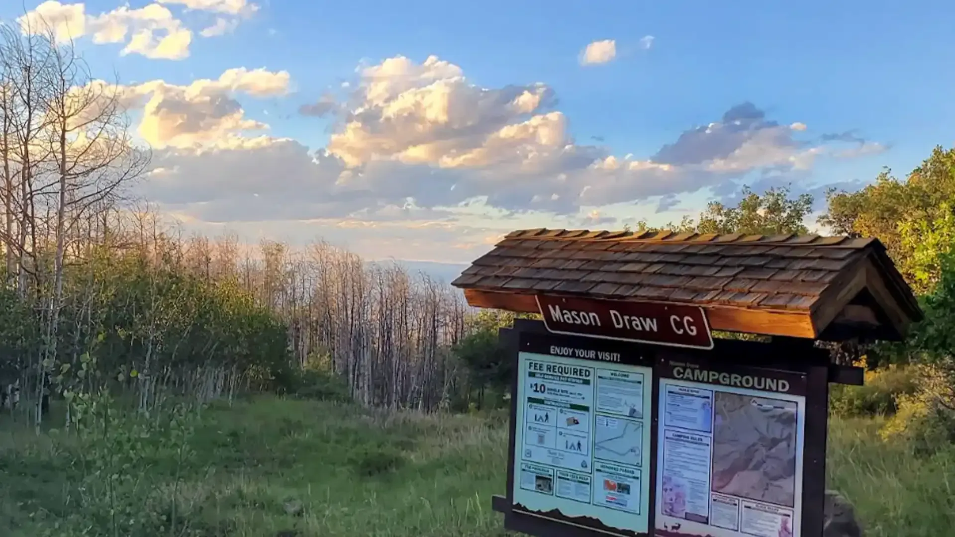 Sign at the Mason Draw campground with maps, clouds, and a sunset view.