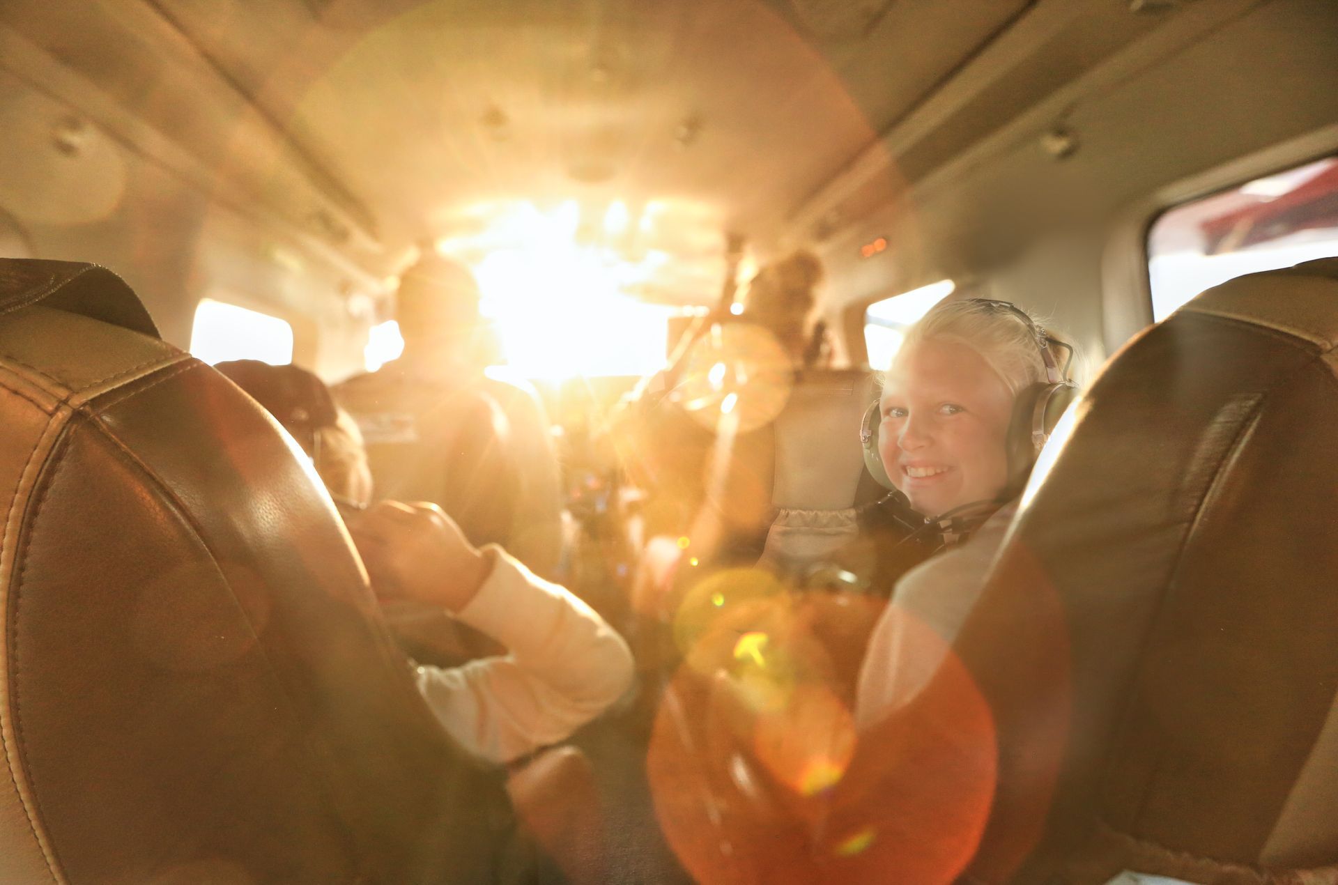Family inside a small airplane smiling as the sun shines through the window.