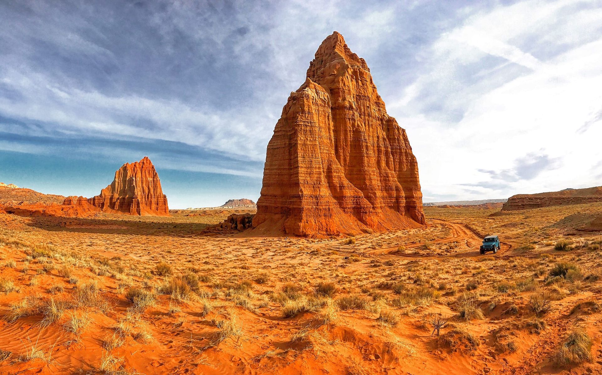Red rock formations in a desert landscape under a cloudy blue sky.