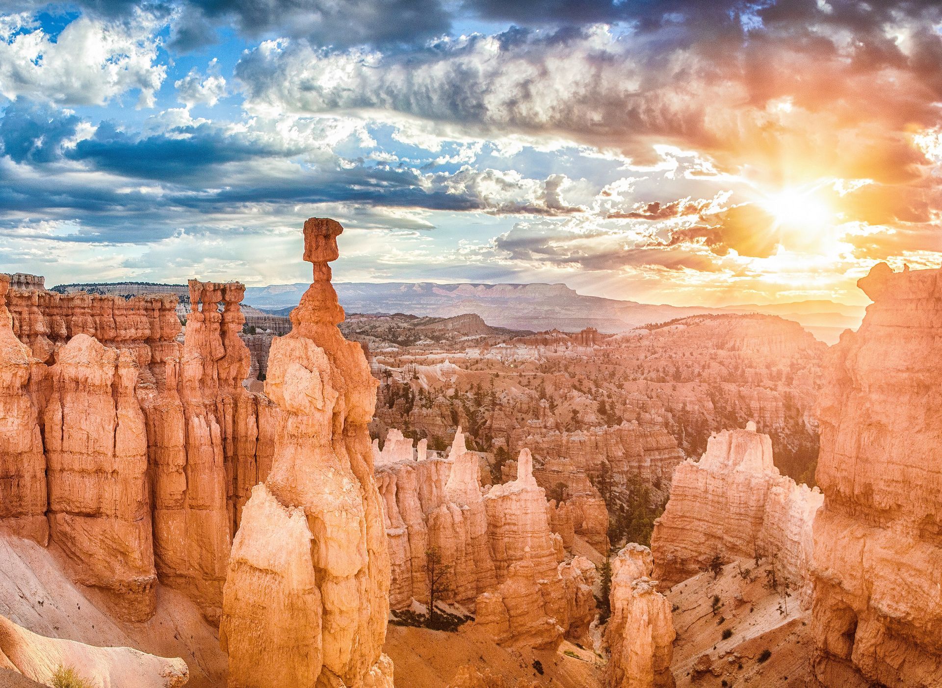 Sunset over Bryce Canyon National Park, Utah; orange hoodoos against cloudy sky.