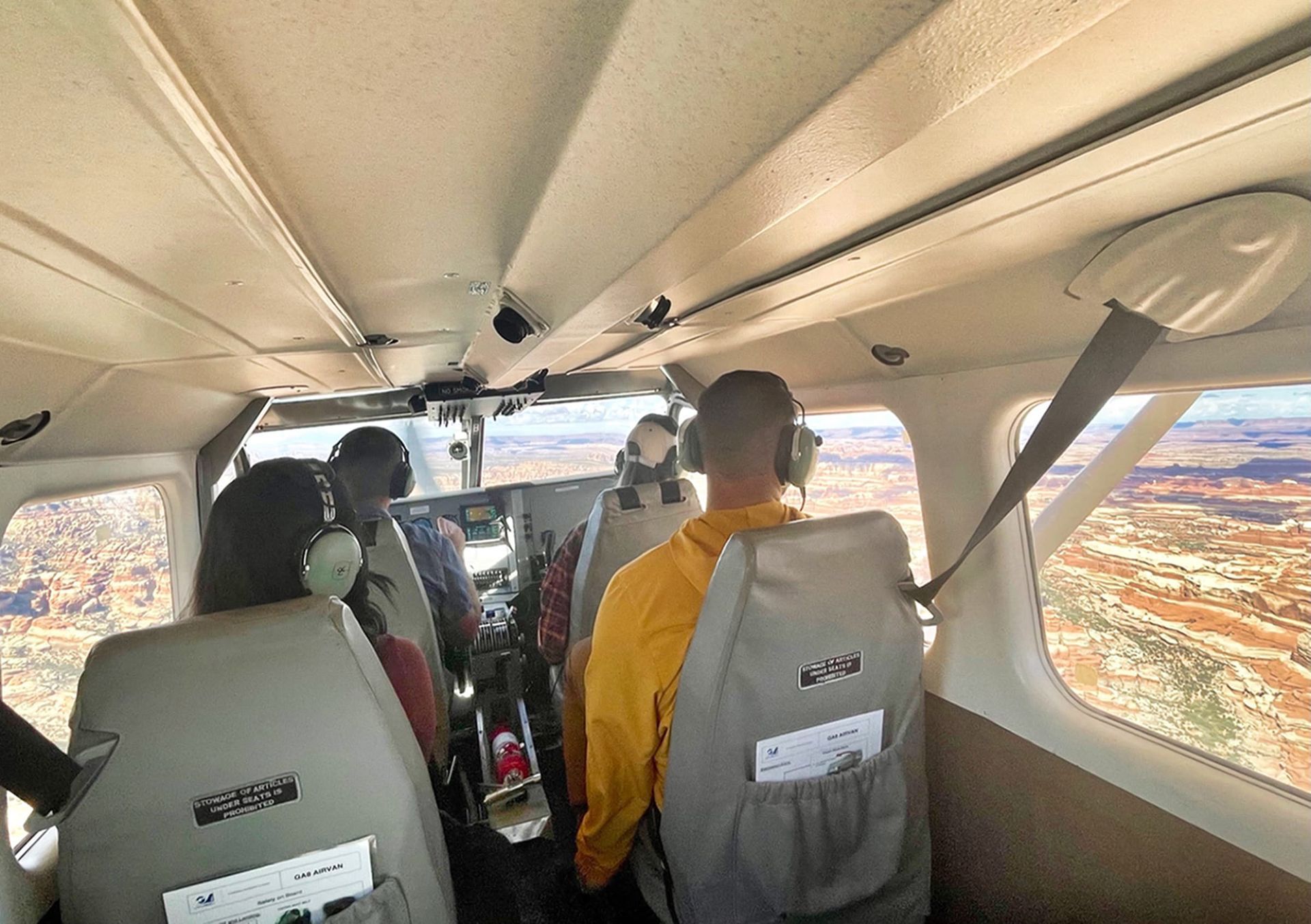 A man in a yellow shirt is sitting in the cockpit of an airplane