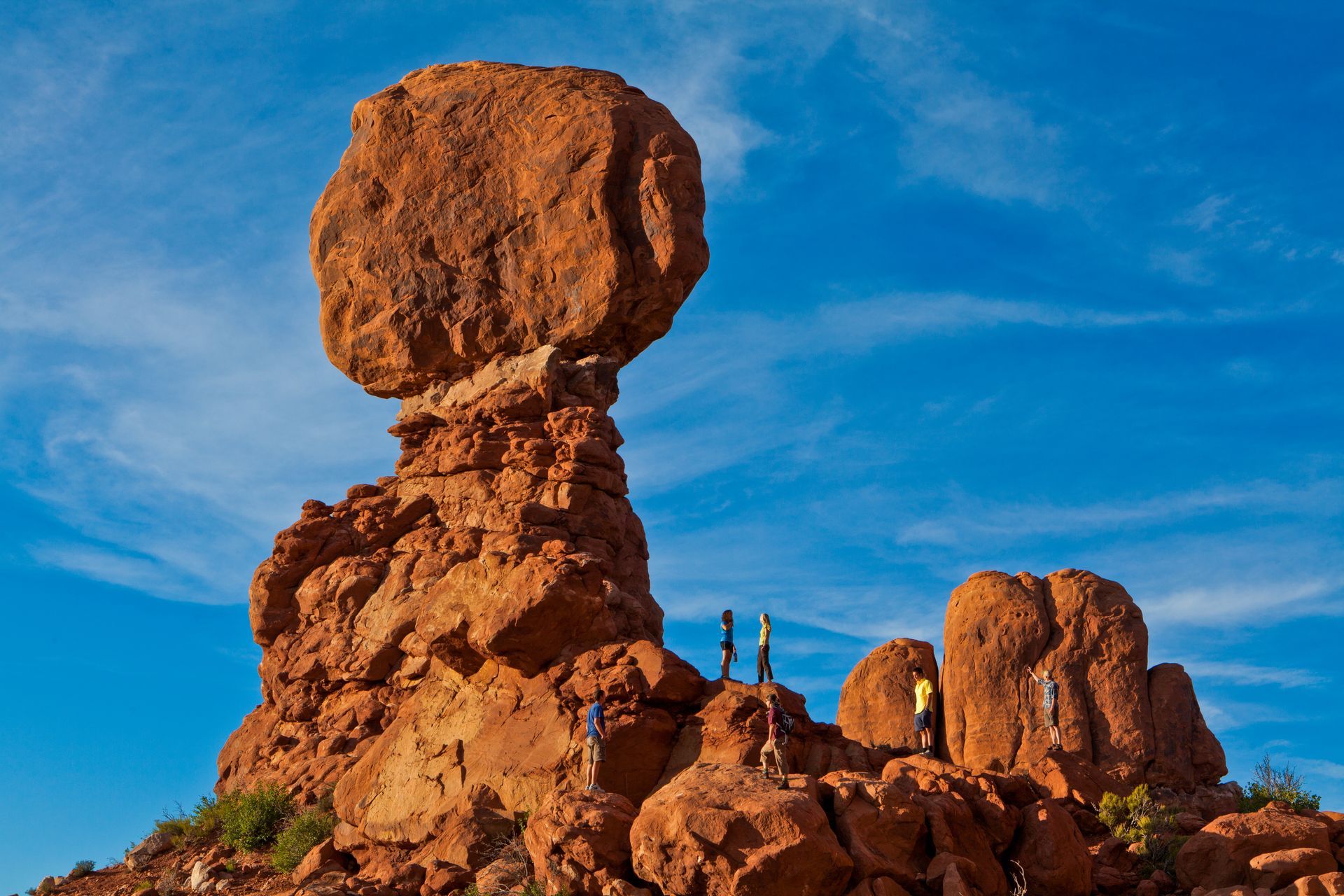 Balanced Rock in Arches National Park, Utah, with blue sky and people on the base.