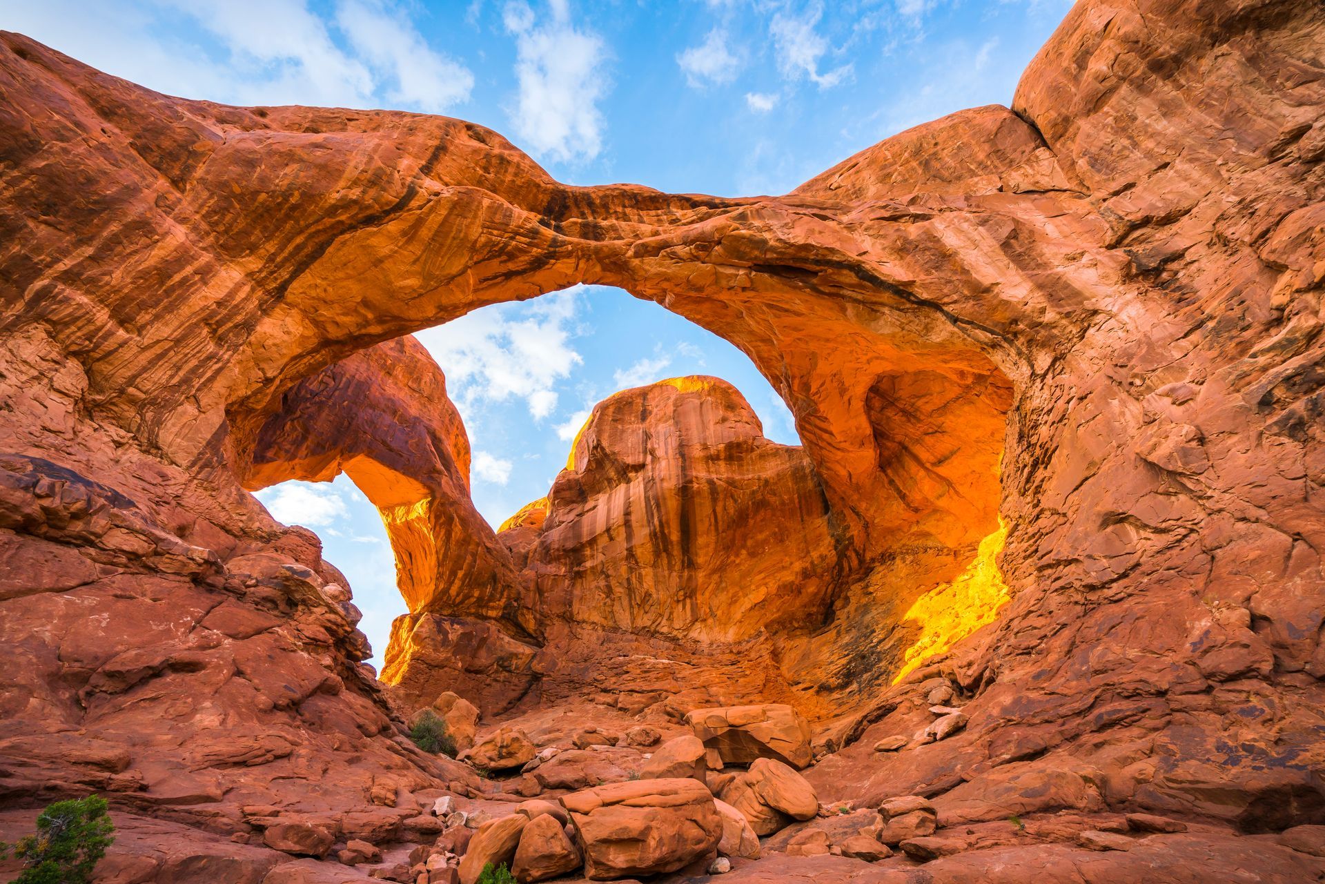 Double Arch rock formation in Arches National Park, Utah, with blue sky visible through the arches.