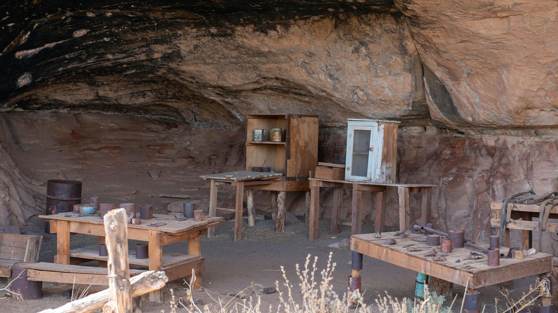 A workshop with wooden tables and cabinets inside a sandstone cave.