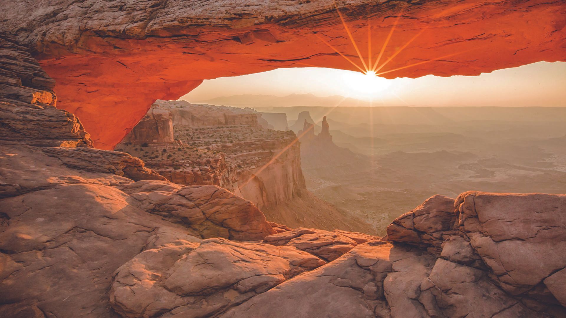 Sunrise through Mesa Arch, Canyonlands National Park, Utah, with orange rock formations.