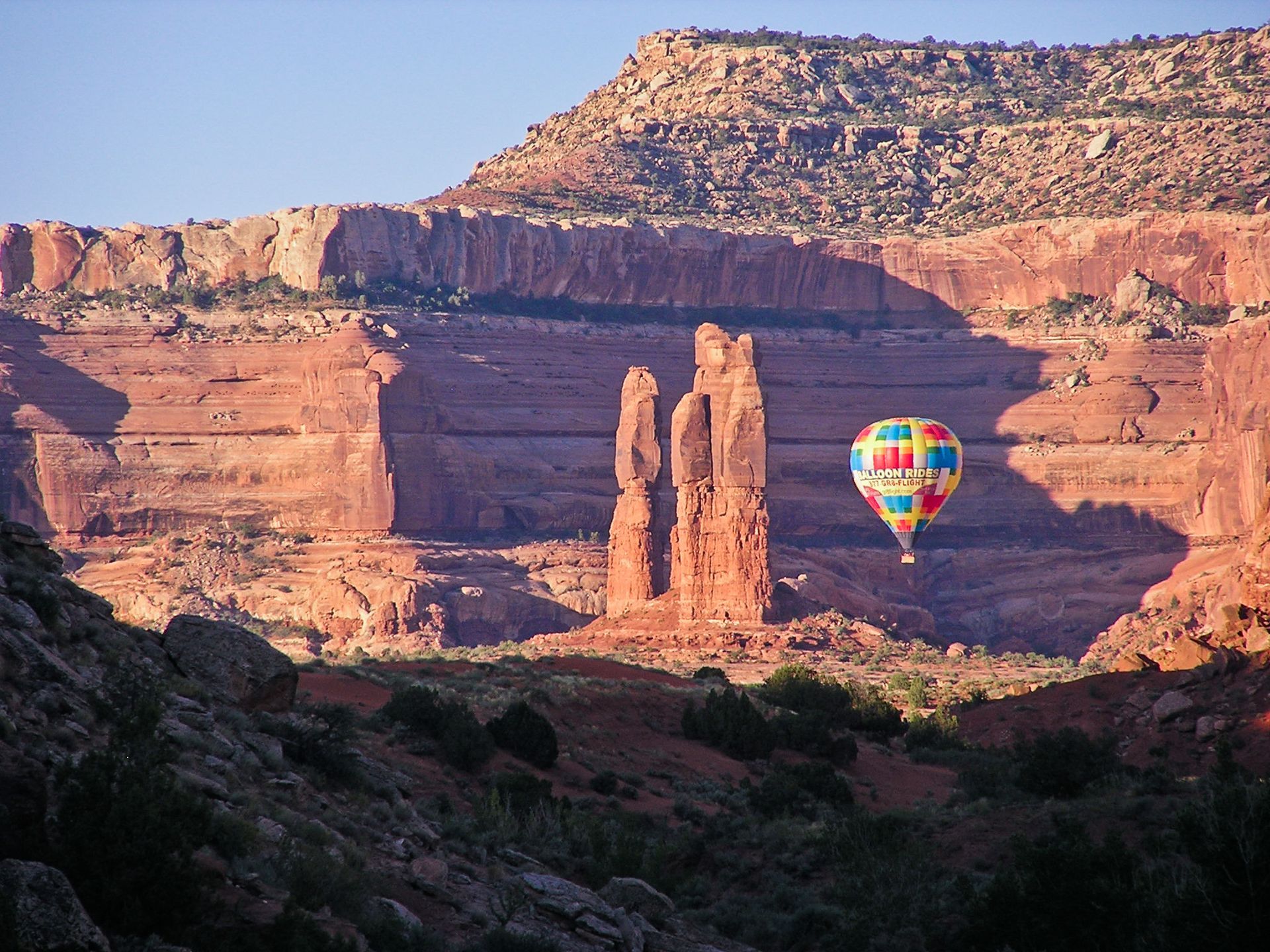 A colorful hot air balloon is flying over a canyon