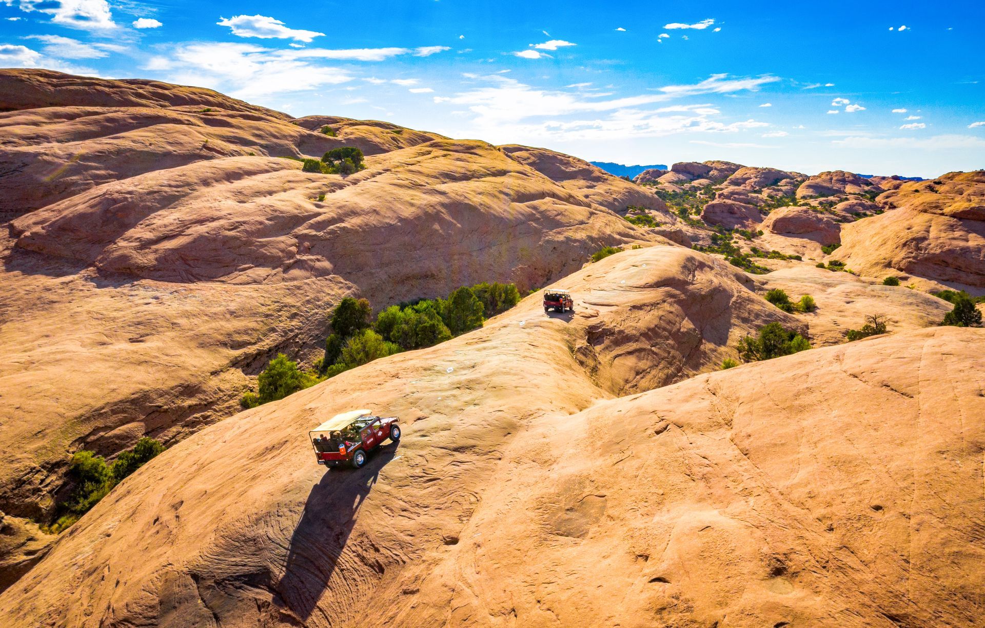 Aerial view of off-road Hummer vehicles driving on the slickrock terrain of the Hells Revenge Trail.