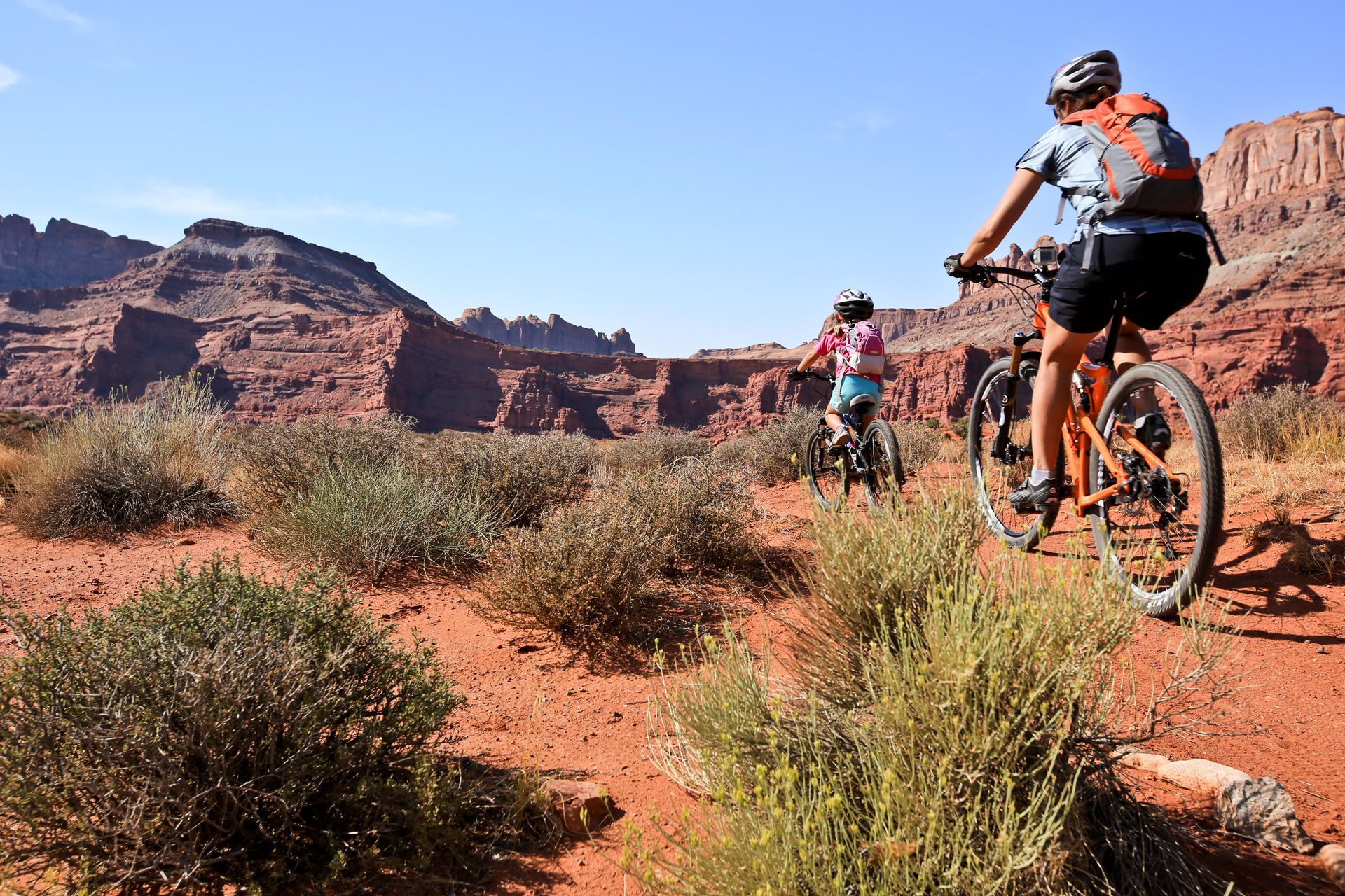 A group of people are riding bikes on a dirt road in the desert.