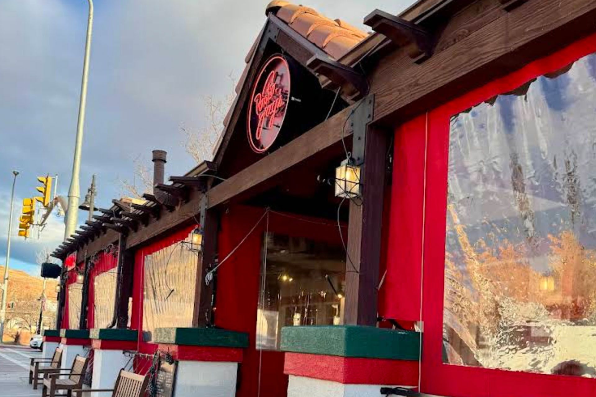 Restaurant with red exterior, wooden accents, clear plastic coverings, and sign.
