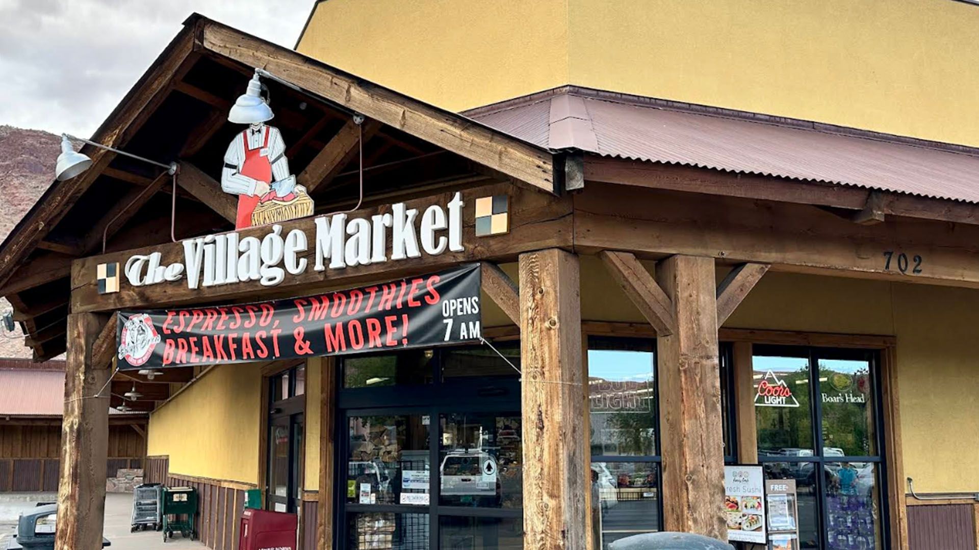 The Village Market entrance with wooden beams and a sign offering groceries and breakfast.