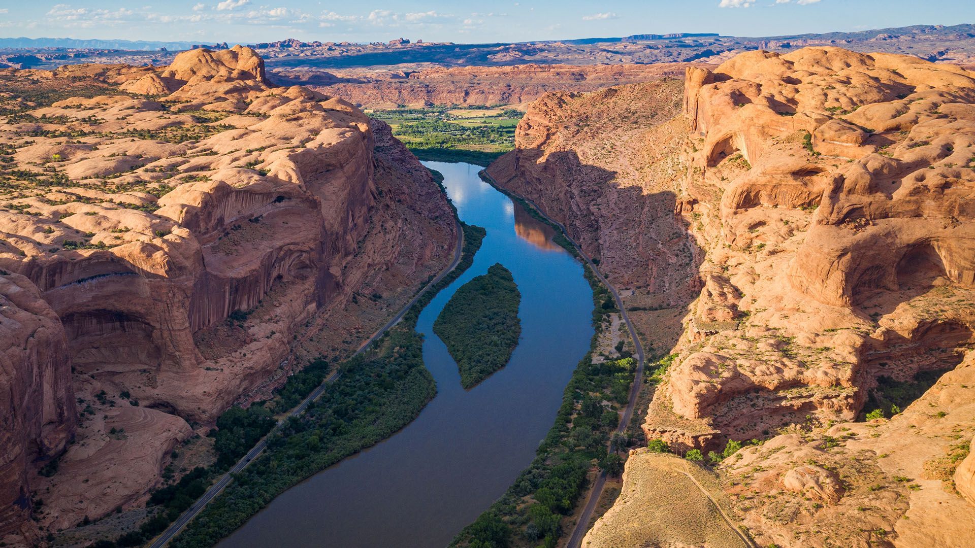 Aerial view of Kane Creek Road winding along the edge of the Colorado River with steep cliffs on either side.