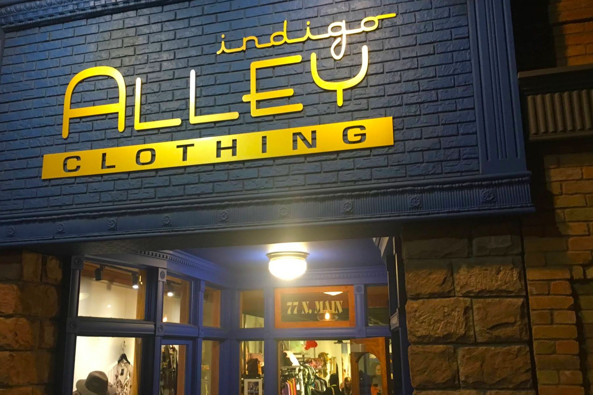 Sign for Indigo Alley Clothing in front of a building made from sandstone bricks.