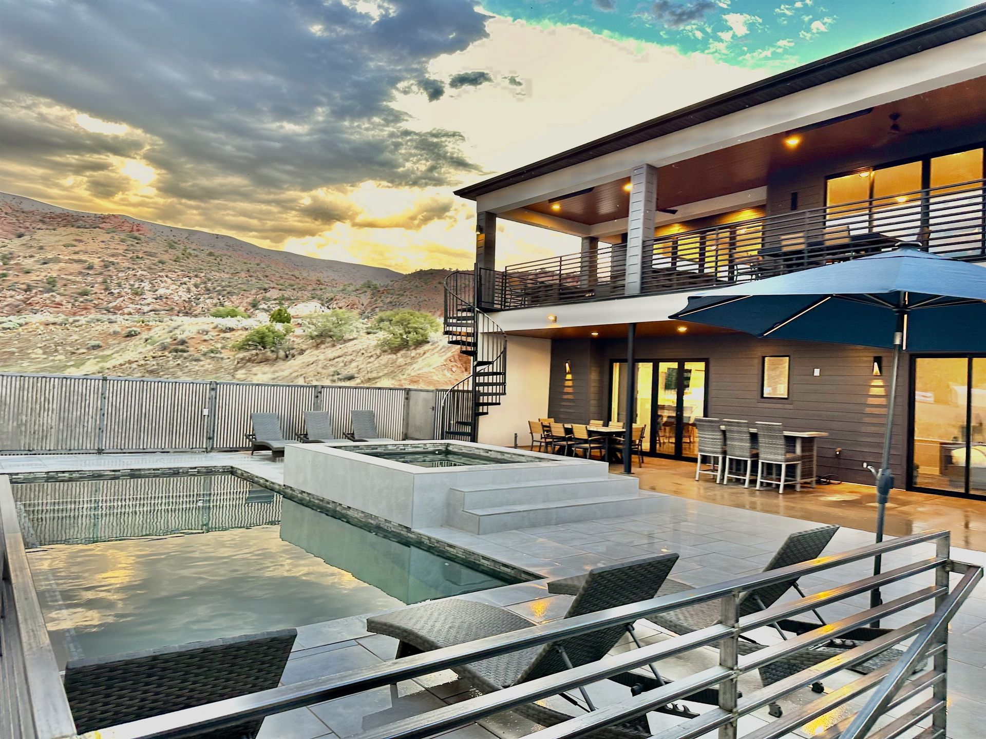 Modern white house with dark trim and garage doors, in desert landscape; SUV parked in driveway.