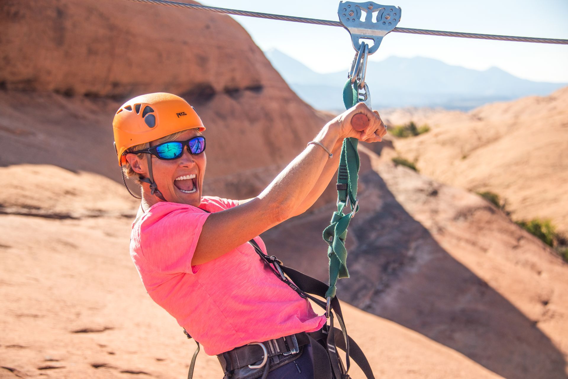 A woman is riding a zip line in the desert.