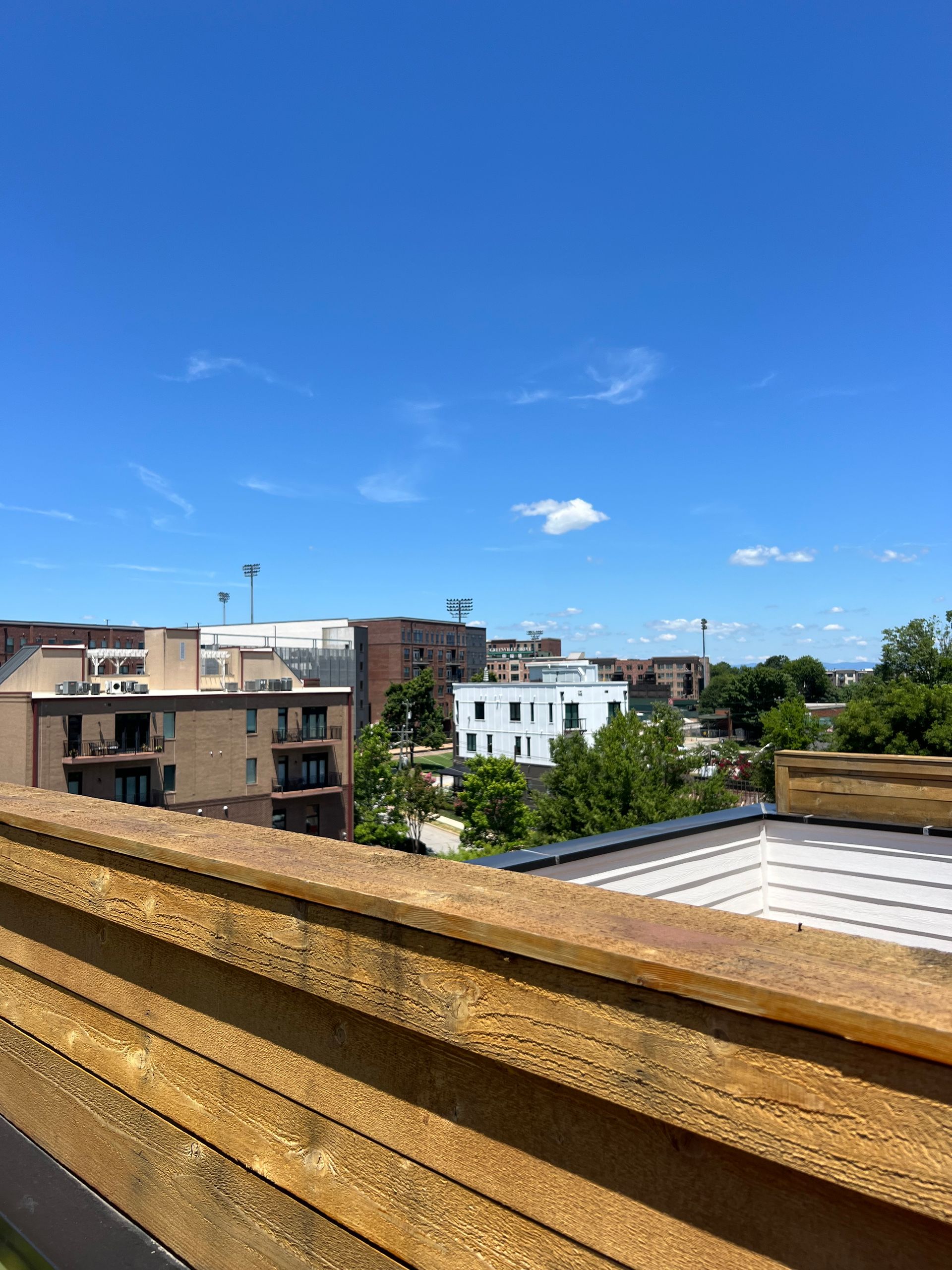 A view of a city from the roof of a building on a sunny day.