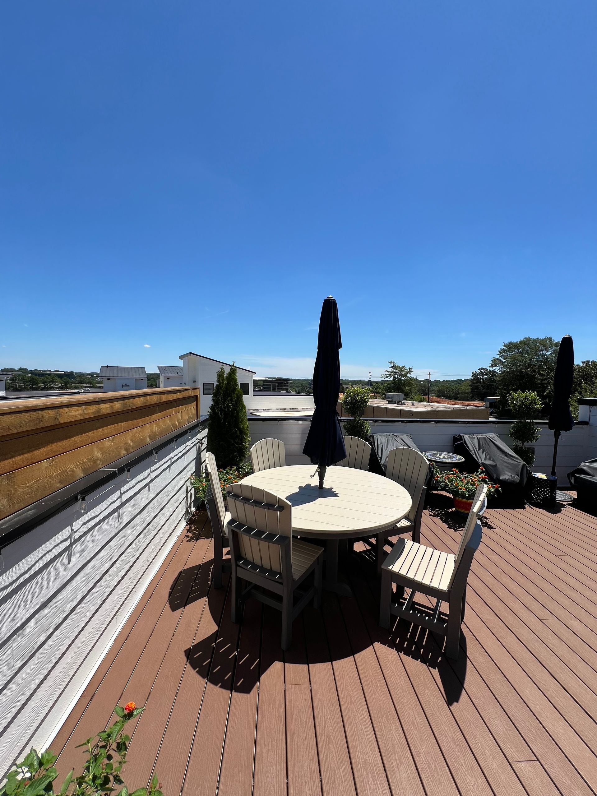 A rooftop deck with a table and chairs and umbrellas