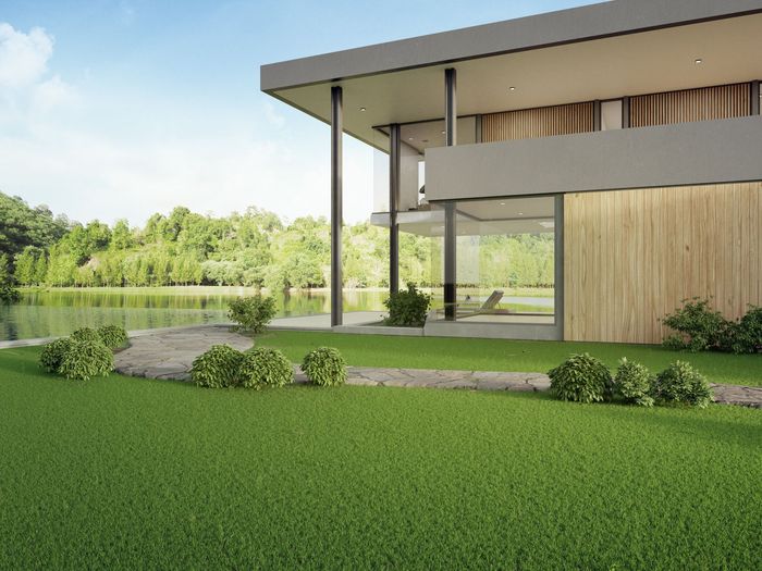 a modern house with a large lawn in front of it and a lake in the background