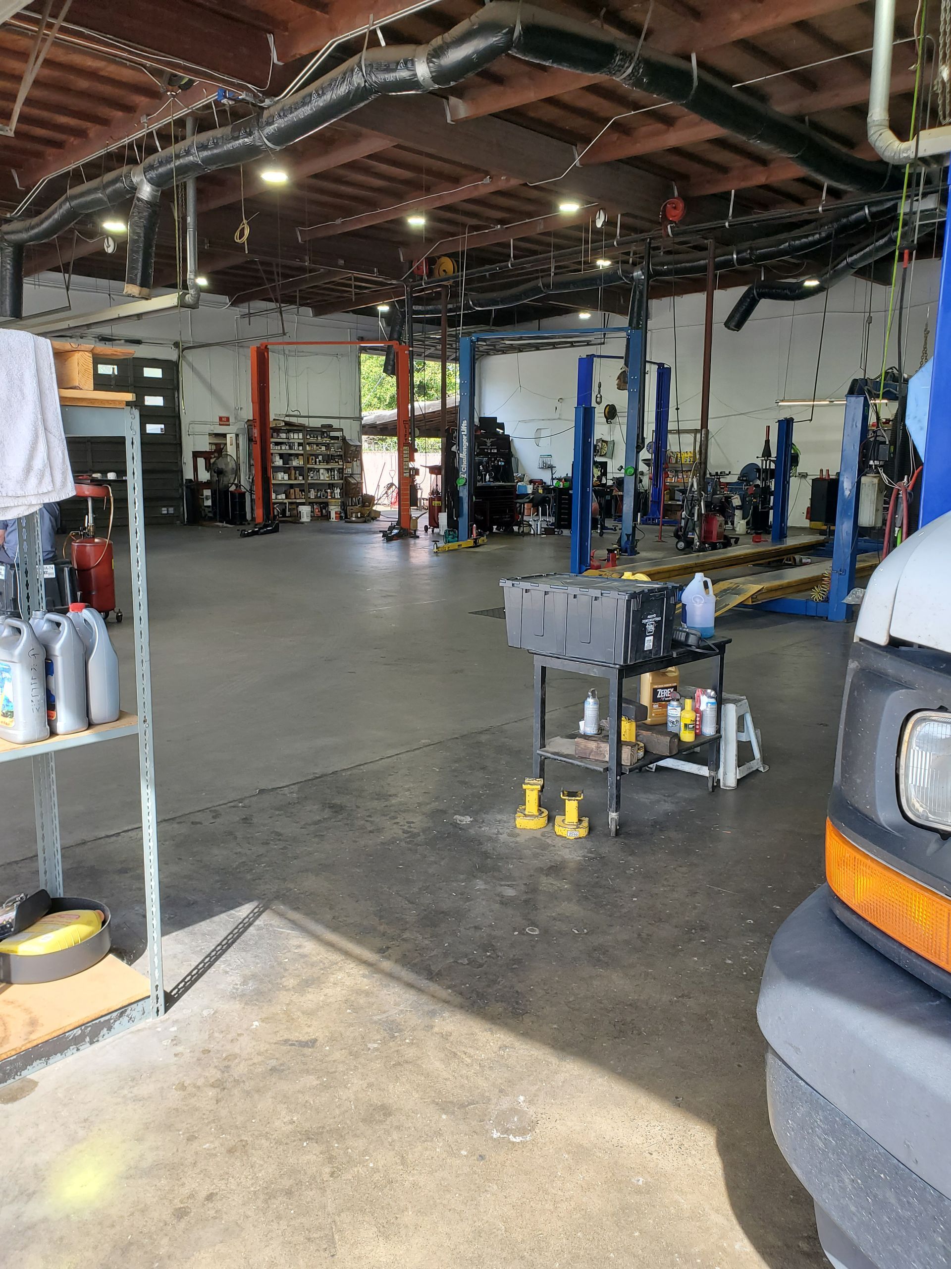 Inside a car repair shop: Tools, lifts, and a vehicle, with a glimpse of the exterior. | Hal's Auto Care