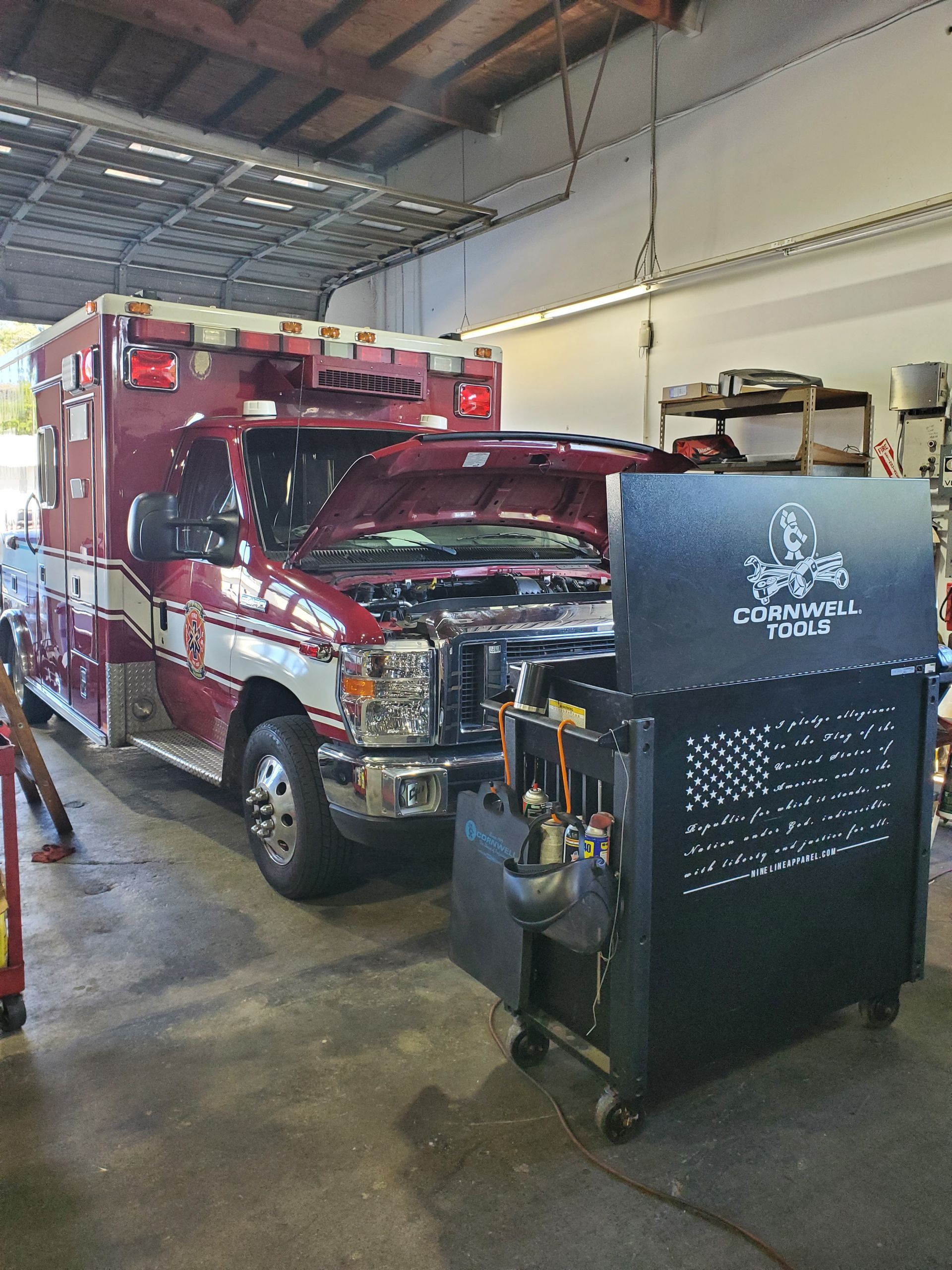 An ambulance with hood open in a garage next to a tool cabinet. Red and white vehicle. | Hal's Auto Care