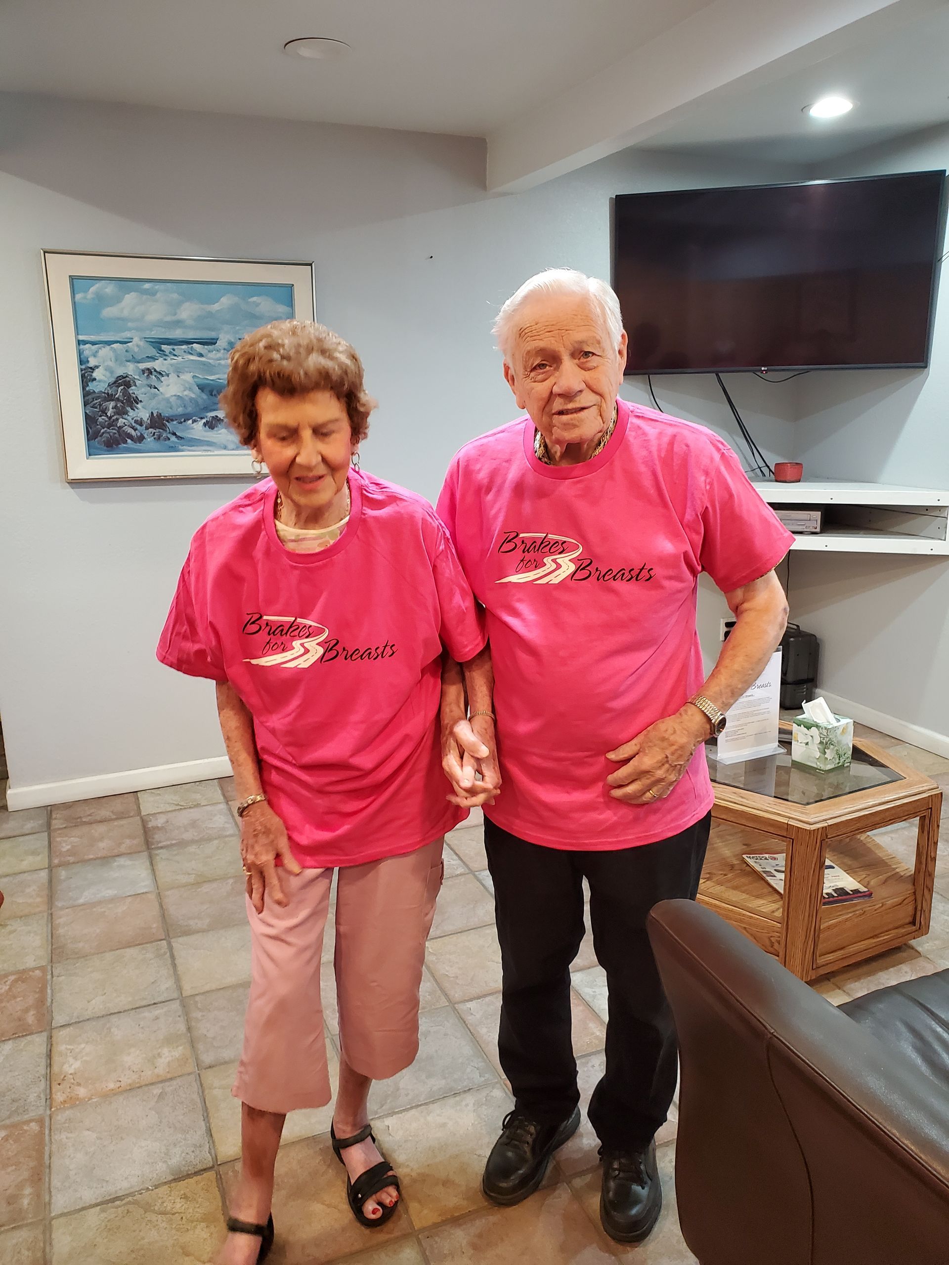 Elderly couple in matching pink shirts, holding hands, in a home. | Hal's Auto Care