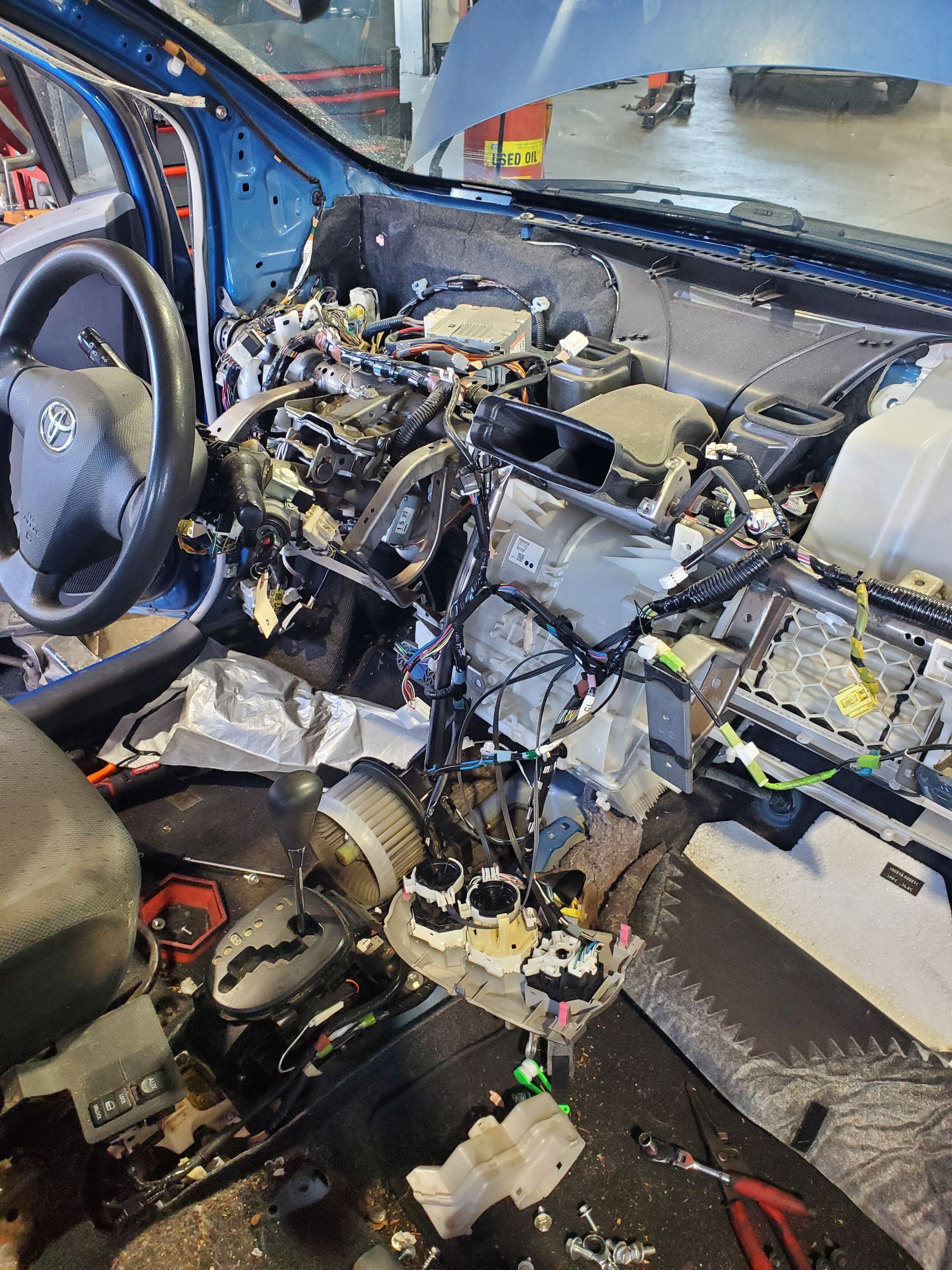 Dashboard of a blue car disassembled, revealing wires and components, in a repair shop. | Hal's Auto Care