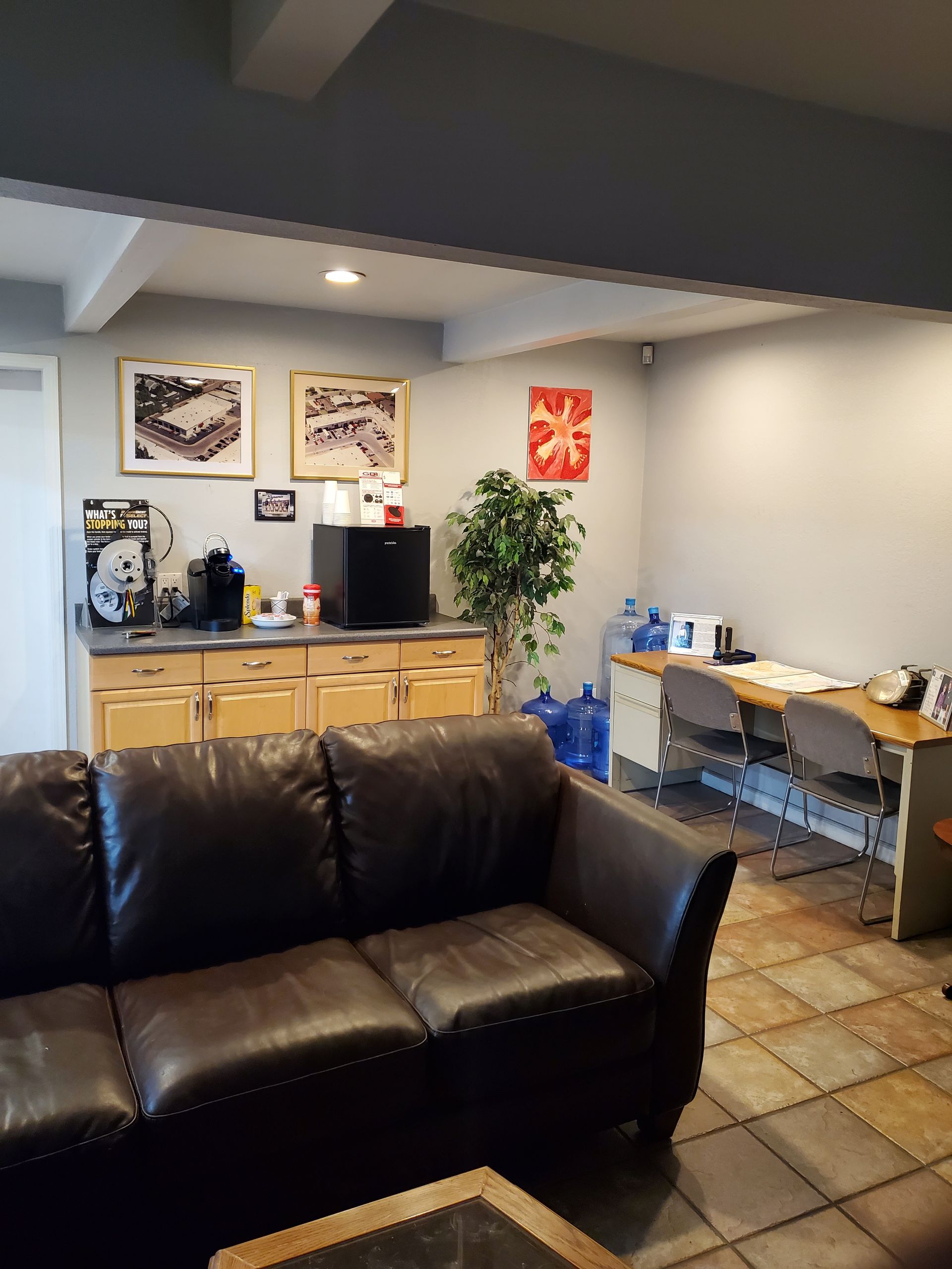 A waiting room with a brown leather sofa, coffee station, and desk. | Hal's Auto Care