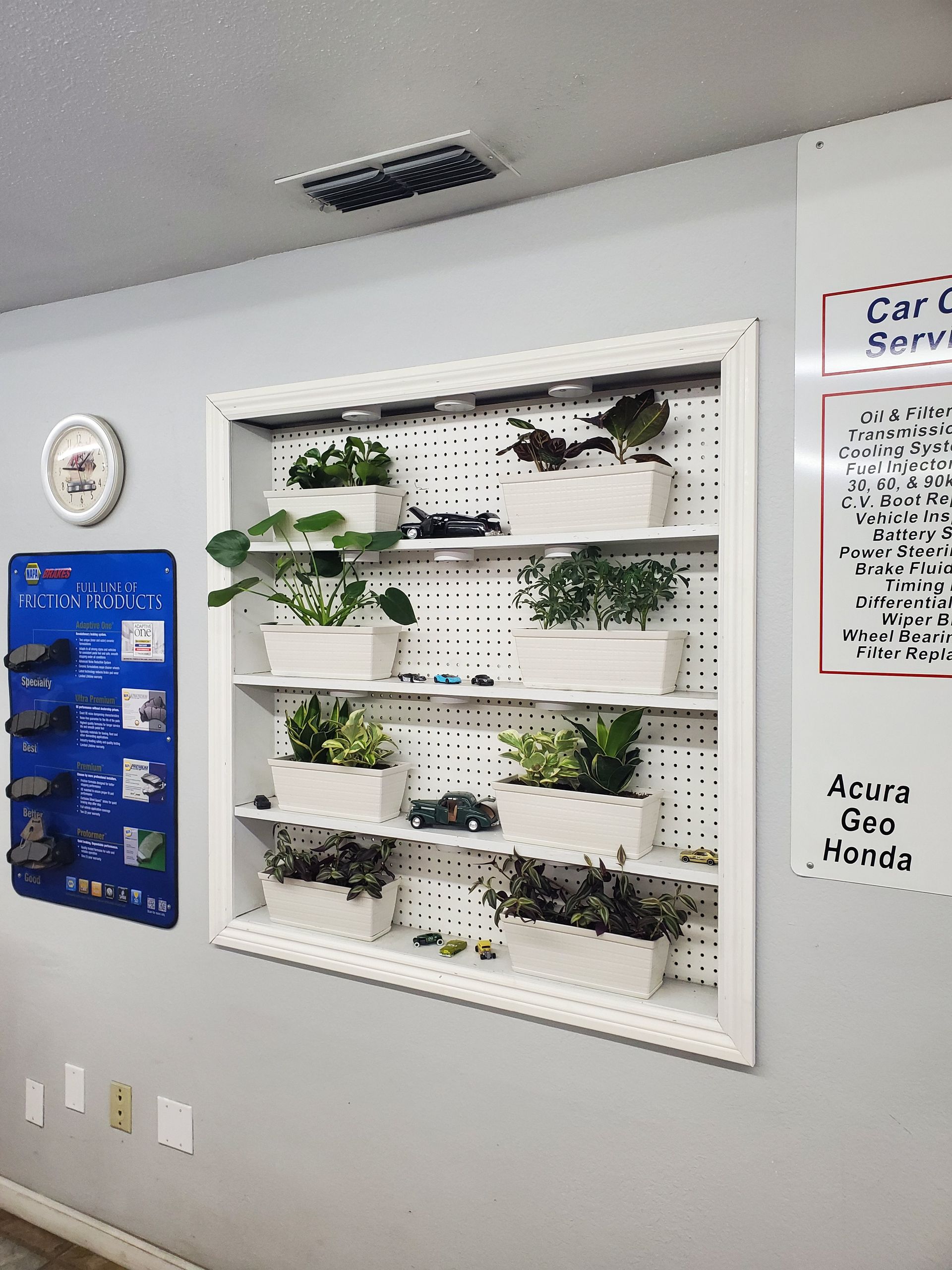 A white pegboard shelf with plants and toy cars inside a shop. | Hal's Auto Care