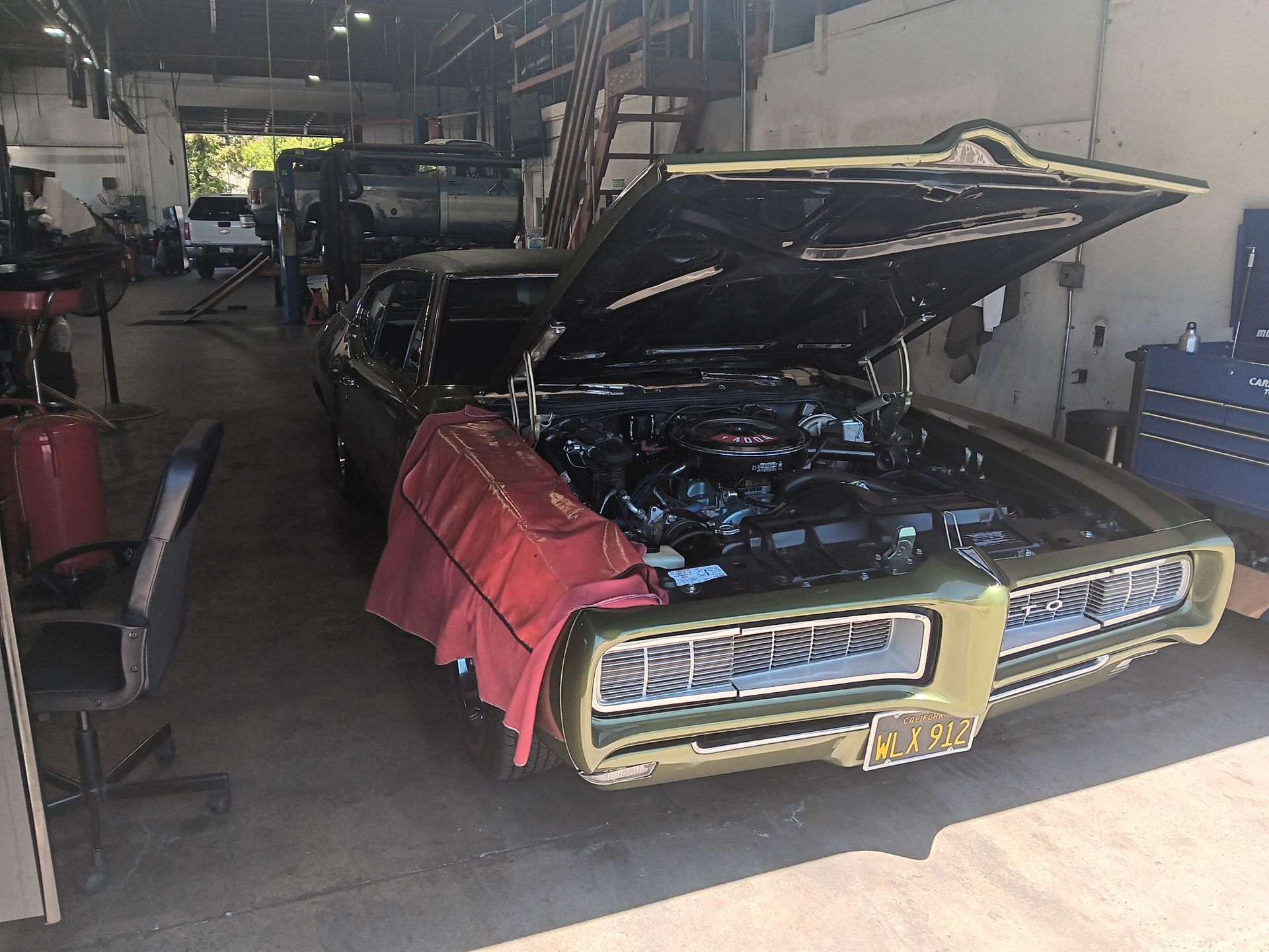 Green classic car with open hood in garage. | Hal's Auto Care