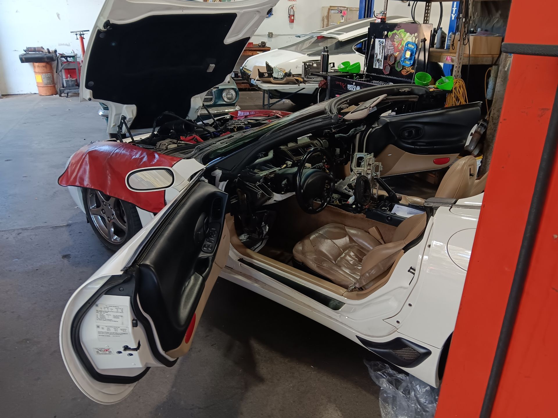 White car with open hood and door in a garage; interior and engine components visible. | Hal's Auto Care