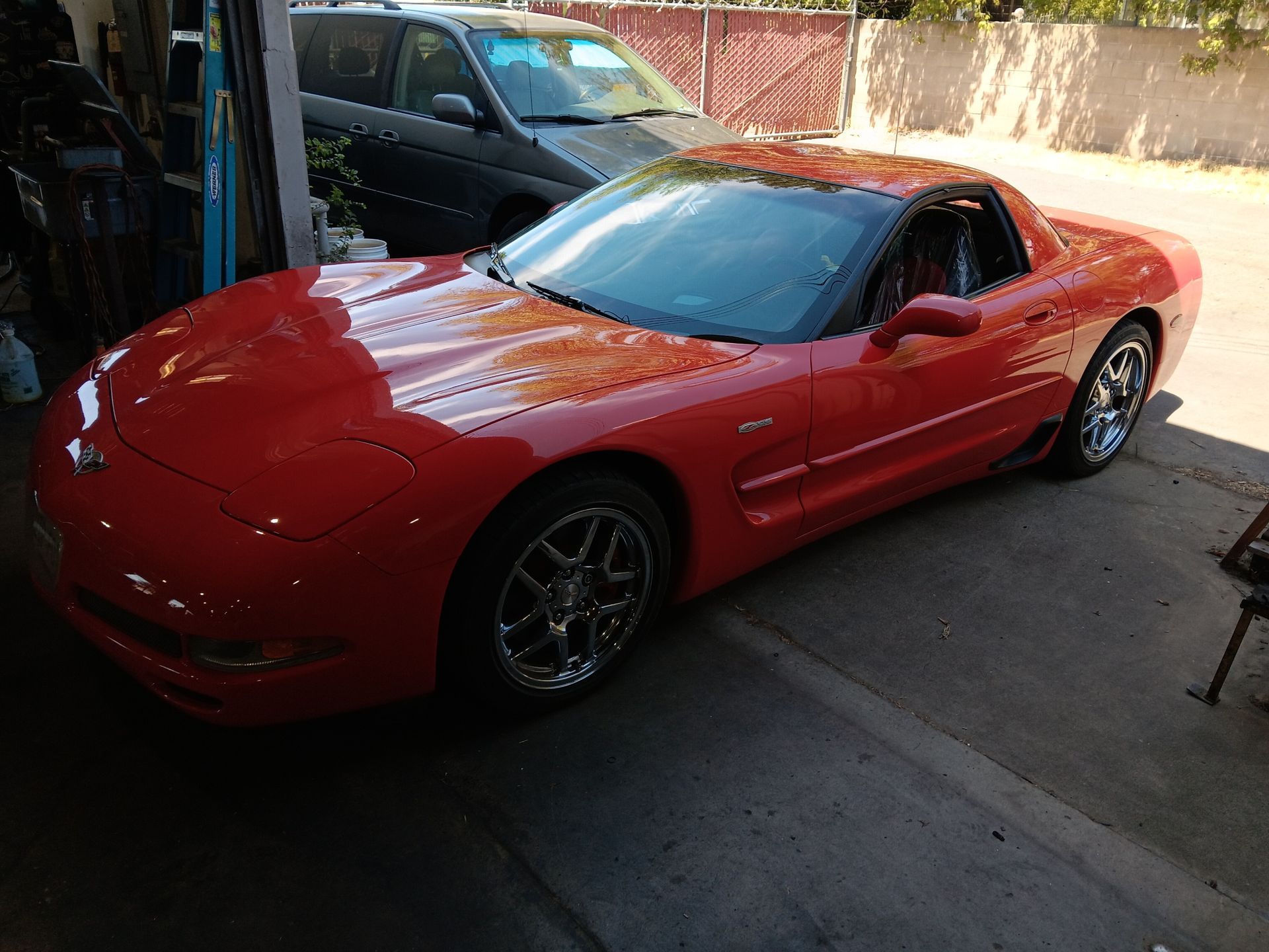 Red Chevrolet Corvette parked in a garage, black roof, chrome wheels, sunny day. | Hal's Auto Care