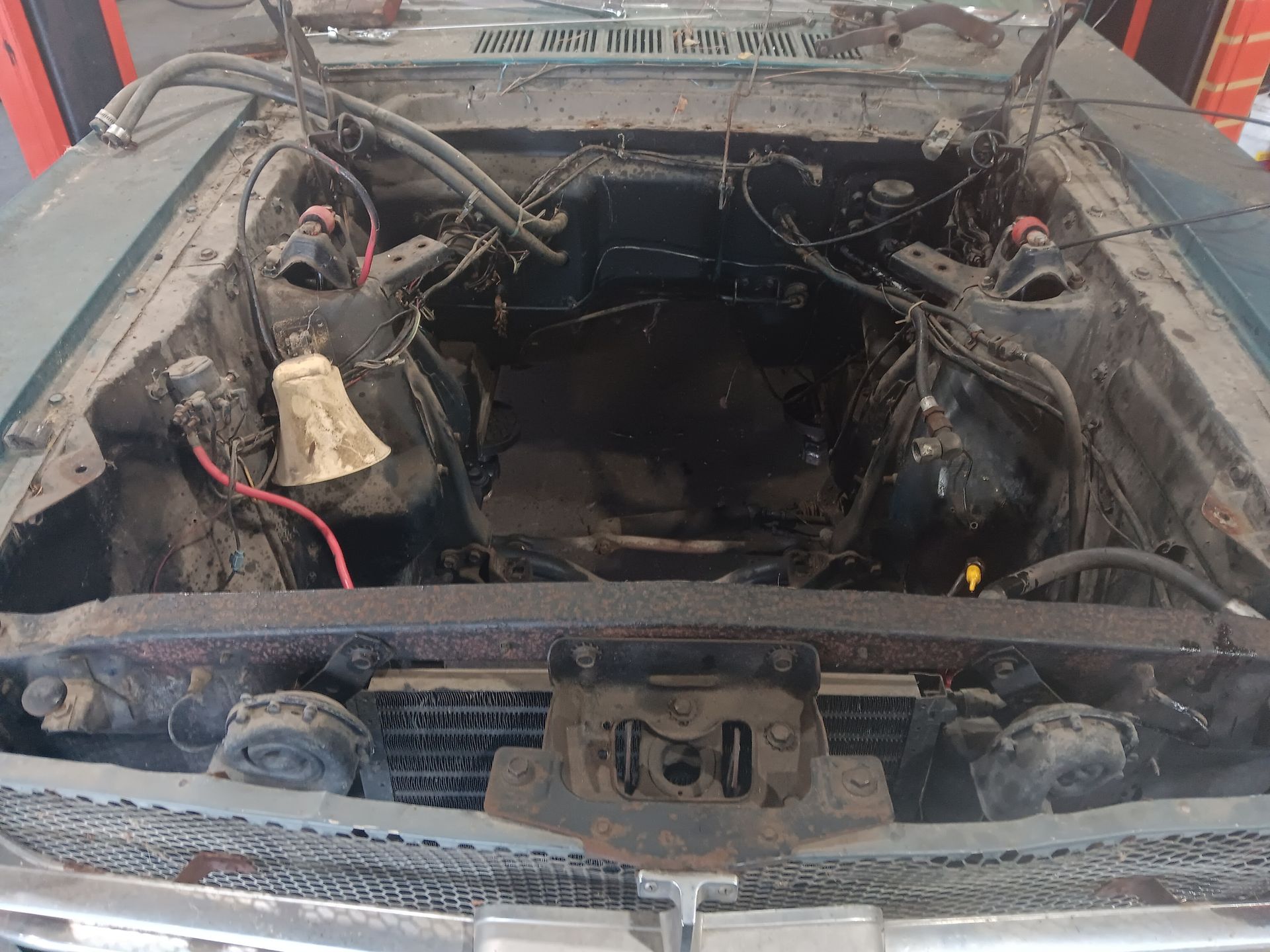 Empty engine bay of a classic car, painted black with visible wiring, under the open hood. | Hal's Auto Care