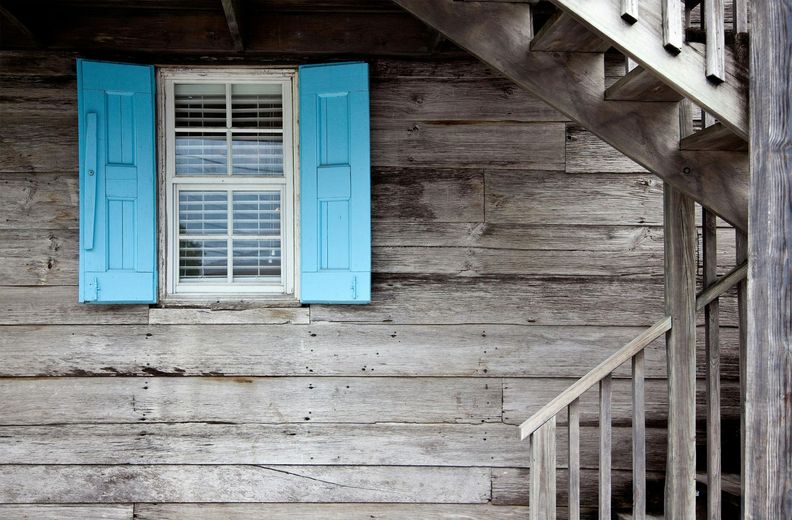 A wooden house with blue shutters and stairs