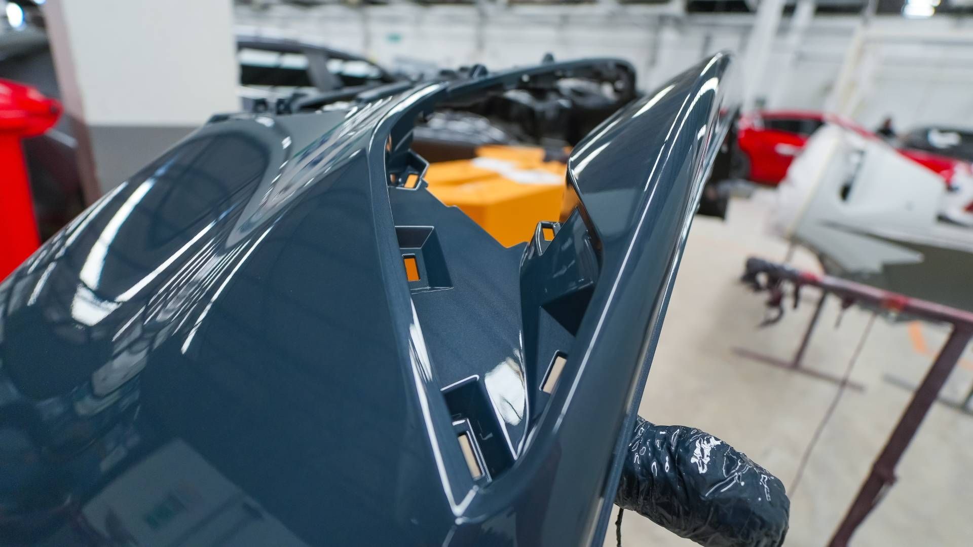 Dark blue car bumper in a workshop, freshly painted.