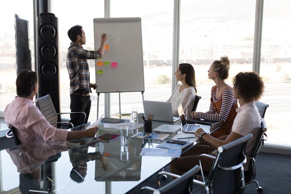 Homem fazendo uma apresentação em uma reunião com colegas. 