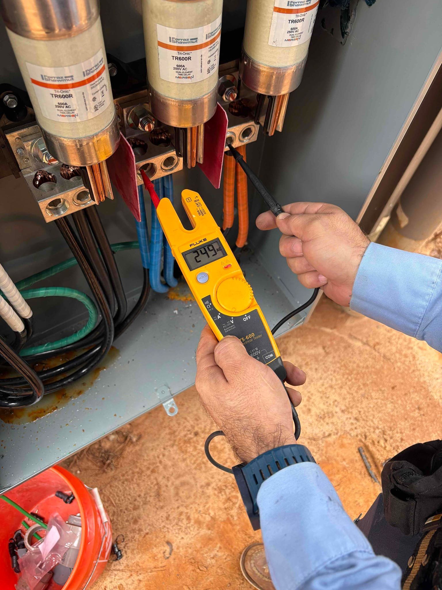 A man in a blue shirt is working on an electrical box.