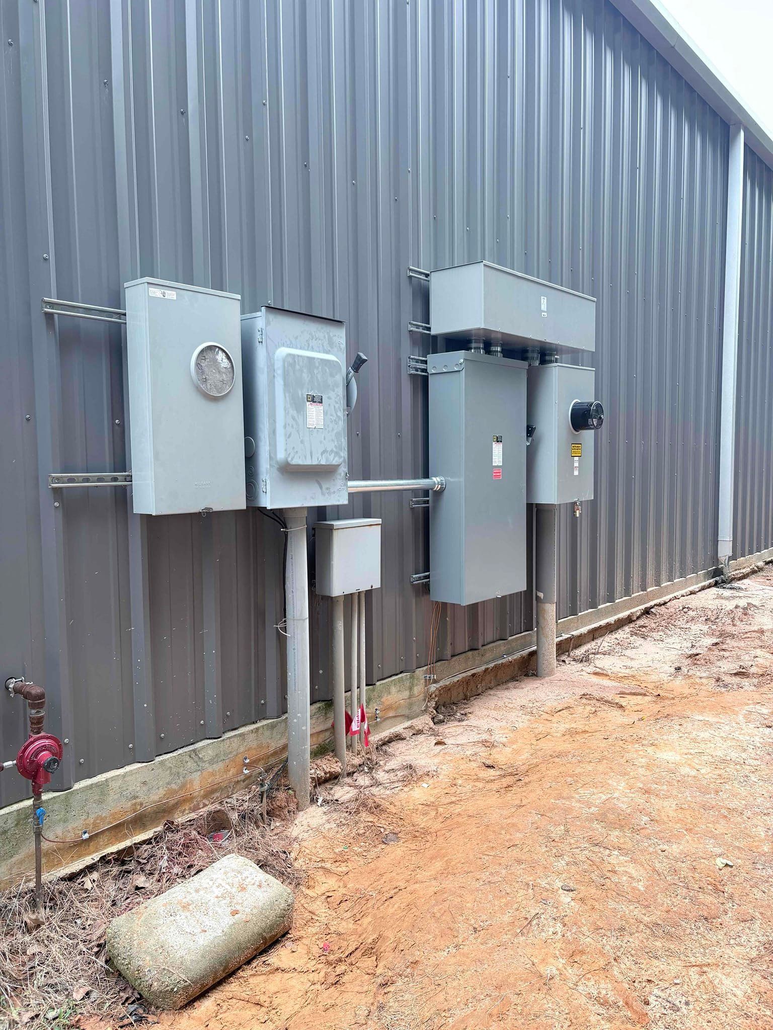 An electrician wearing a mask and gloves is working on an electrical box.