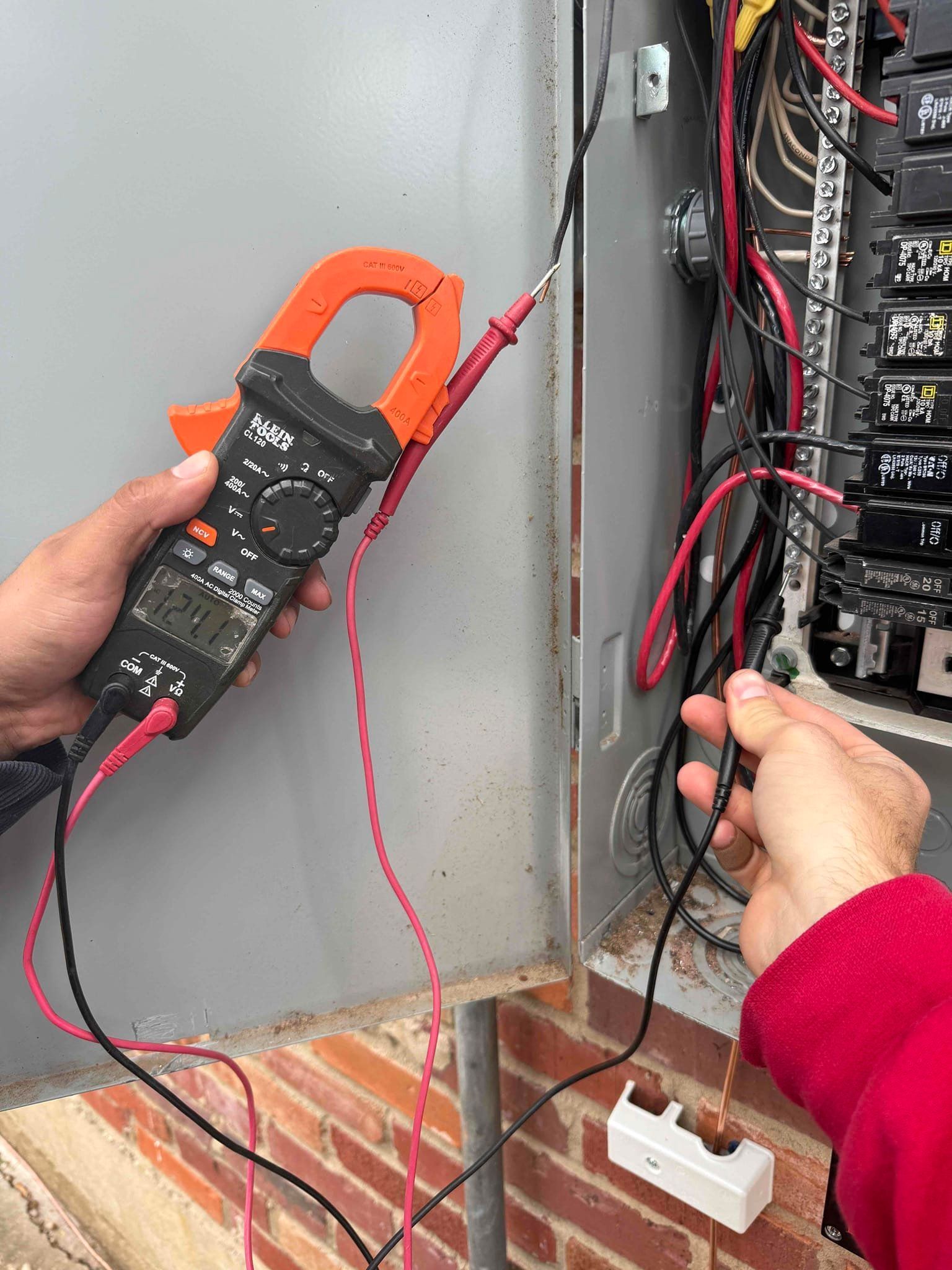 A man is working on a electrical panel with a screwdriver.