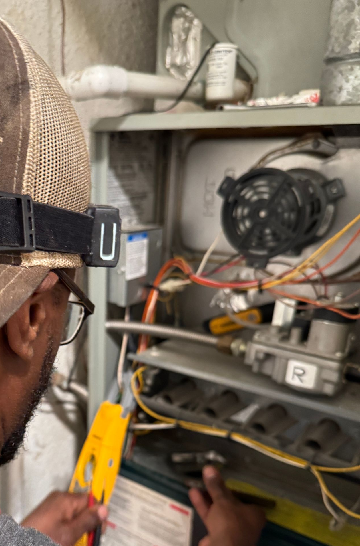 Man in blue shirt repairs a white radiator with a wrench.