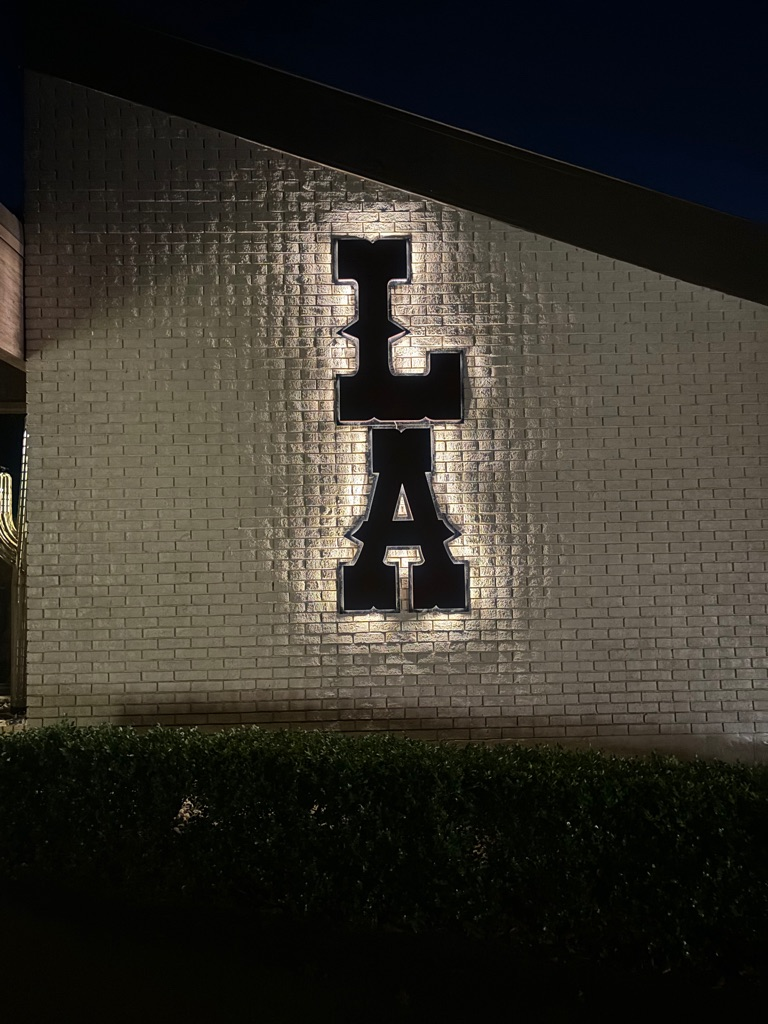 A living room with a couch , two chairs , a table , and a chandelier.