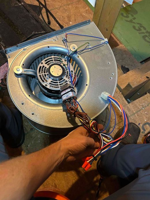 Technician repairs a gas boiler, focused on internal components, wearing glasses and a hard hat.