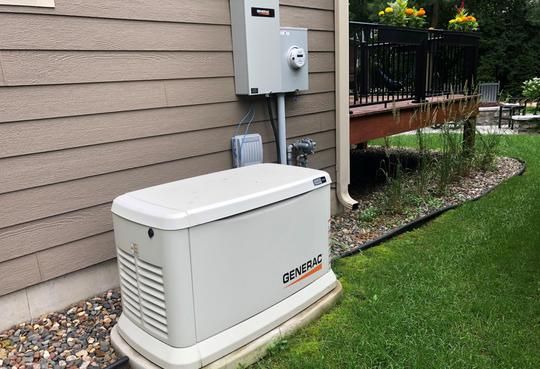 A white generator is sitting on the side of a house.