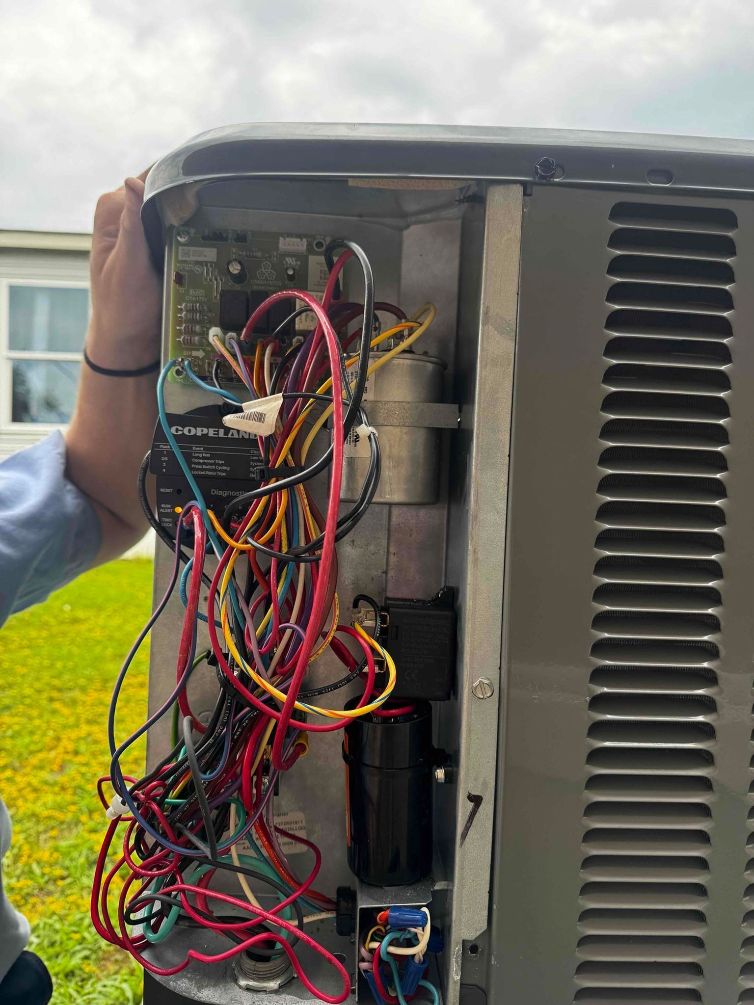 A man is fixing an air conditioner with a screwdriver.
