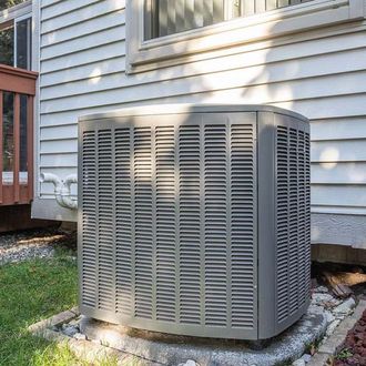 A large air conditioner is sitting on the side of a house.