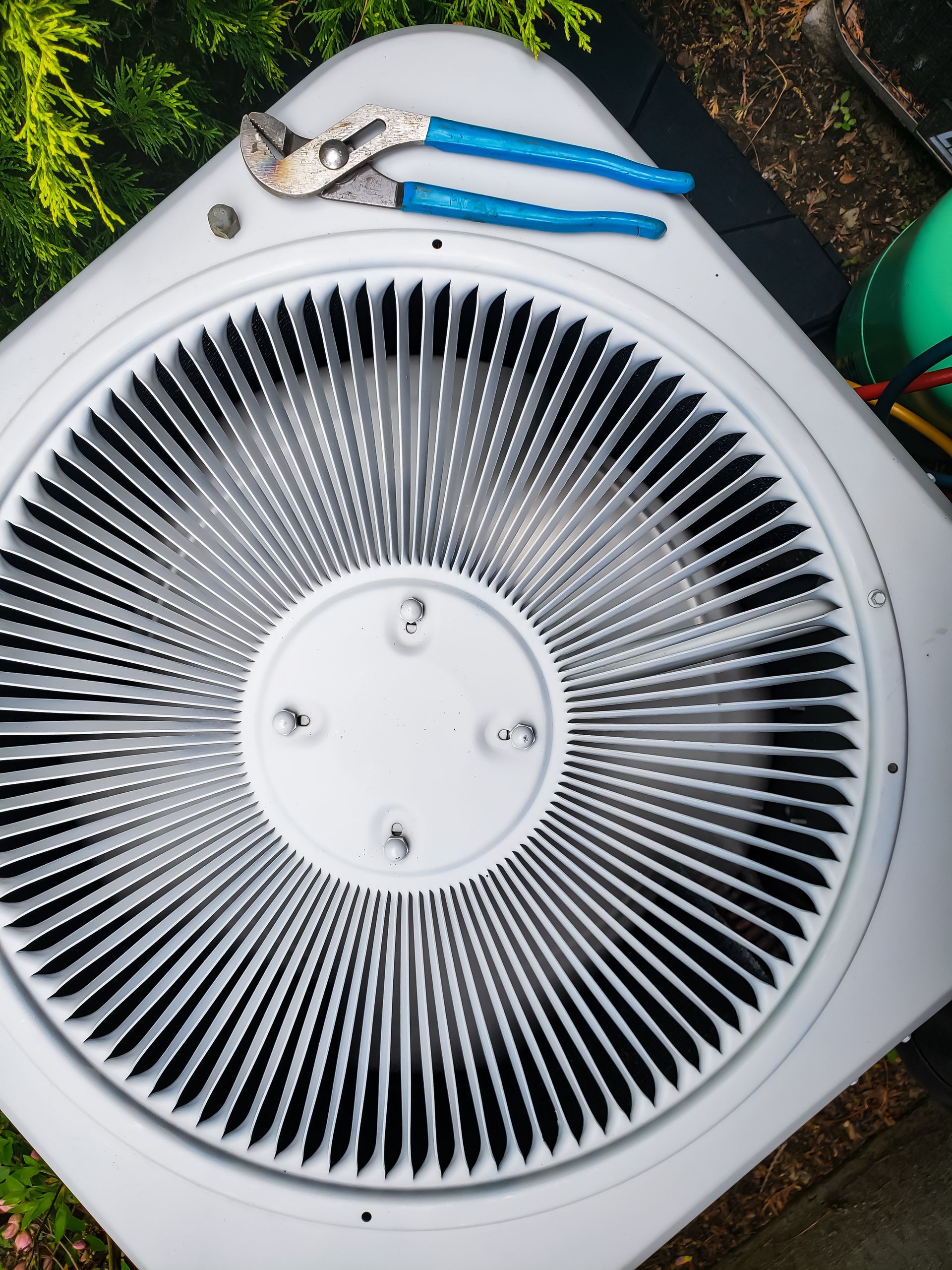 A pair of pliers sit on top of an air conditioner