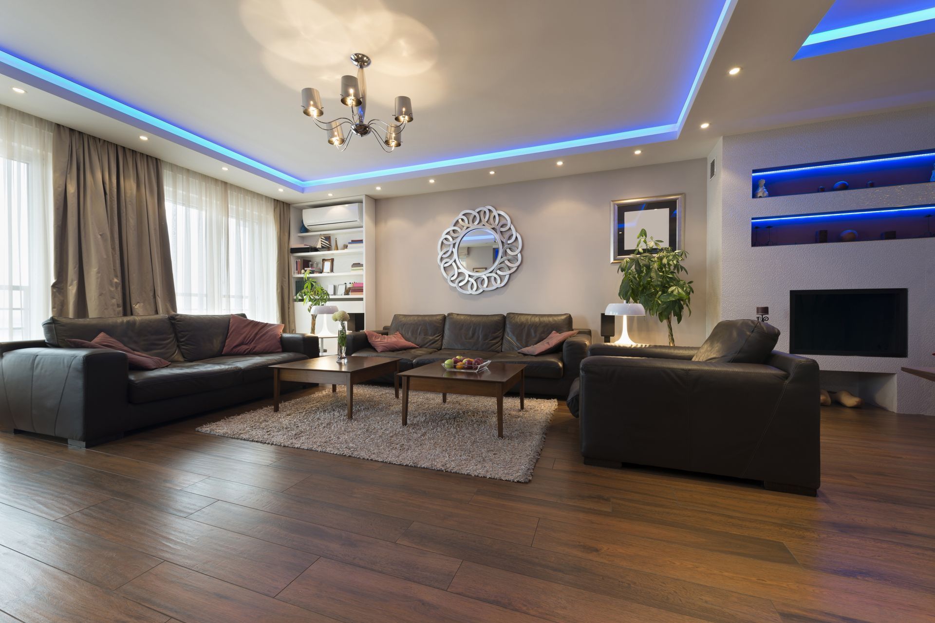 A living room with a couch , two chairs , a table , and a chandelier.