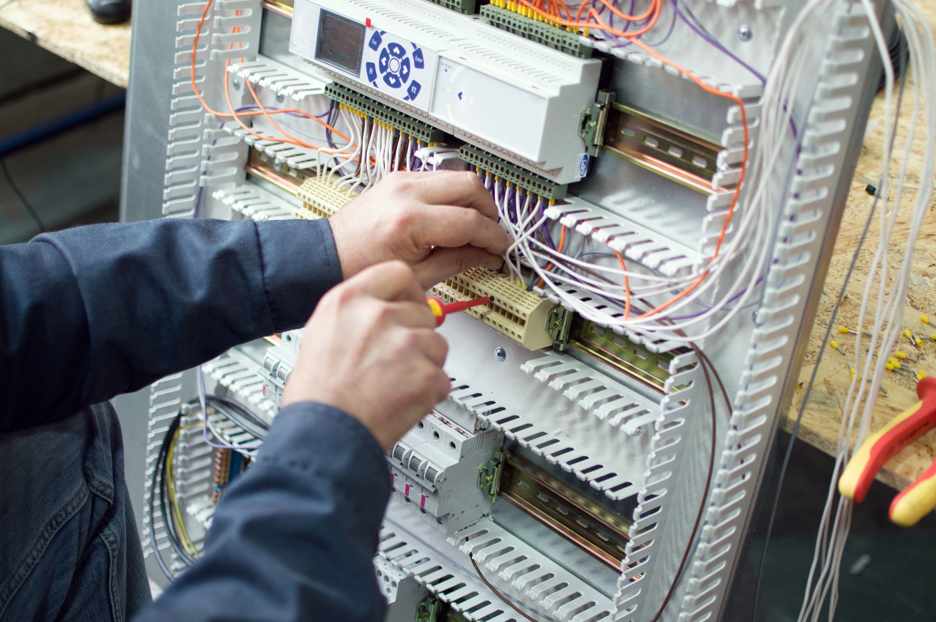 A man is working on a electrical panel with a screwdriver.