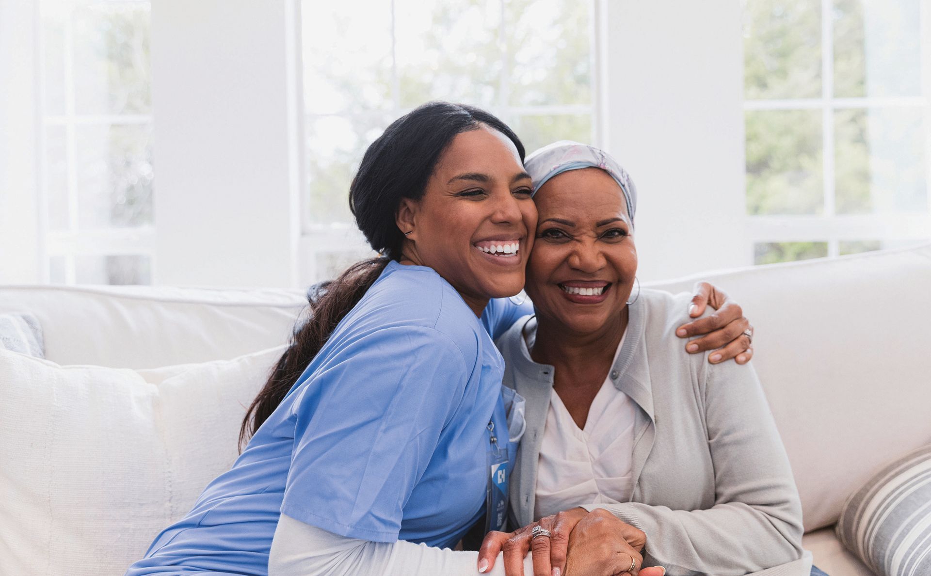 a nurse is hugging an older woman on a couch