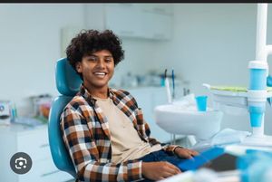 A young boy is sitting in a dental chair while a dentist examines his teeth.