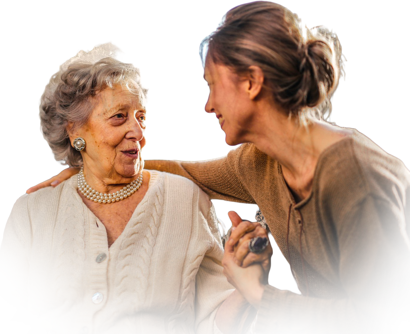 A person with a warm expression places a hand on the shoulder of another person, both smiling gently as they hold hands.