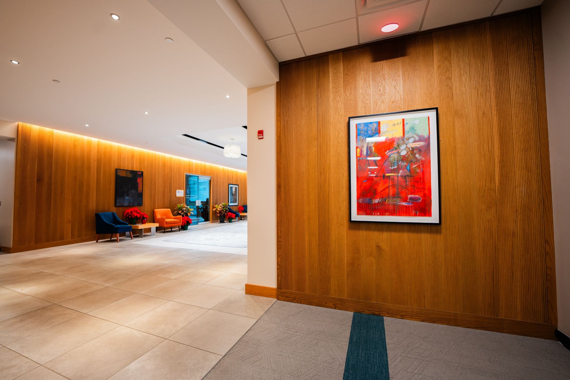 Hallway with wood paneling, art, and seating area in the background.